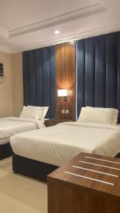 a hotel room with two beds and a table at واحة طيبة للشقق الفندقية in Al Madinah