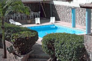 una piscina con 2 sillas de césped y arbustos en Pousada Abais, en Aracaju