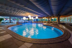 a large swimming pool in a building with windows at Hotel Mioni Royal San in Montegrotto Terme