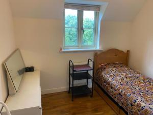 a bedroom with a bed and a chair under a window at Cotswolds house in Cirencester