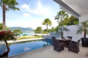 ein Haus mit einem Pool, einem Tisch und Stühlen in der Unterkunft Atika Villas in Patong Beach