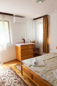 a bedroom with two beds and a dresser and windows at Apartment R. Dermendzhiev in Melnik