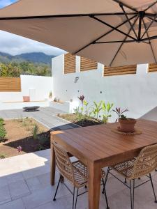 une table et des chaises en bois avec un parasol dans l'établissement Villa Couleur Nature, à Salazie