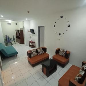 una sala de estar con sofás y un reloj en la pared en Sewa Rumah Harian 3 BR di Bandung,Kiaracondong, en Bandung