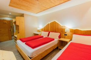 a bedroom with two beds and wooden walls at Garni Francescato in Livigno
