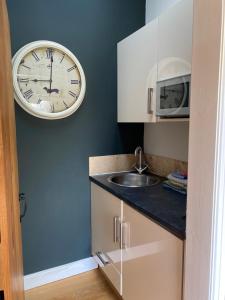 cocina con reloj en la pared y fregadero en The Brosterfield Suite - Brosterfield Farm, en Bakewell