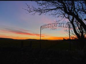 un coucher de soleil avec un panneau indiquant la ferme prévue dans l'établissement The Brosterfield Suite - Brosterfield Farm, à Bakewell