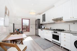 uma cozinha com armários brancos e uma mesa de madeira em Lisboa Tejo Apartment @ Stay like a local at Algés em Cruz Quebrada