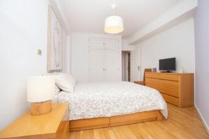 um quarto branco com uma cama e uma televisão em Lisboa Tejo Apartment @ Stay like a local at Algés em Cruz Quebrada