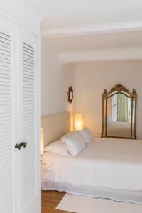 um quarto com uma cama branca e um espelho em Grand Hôtel De Cala Rossa & Spa Nucca em Porto-Vecchio