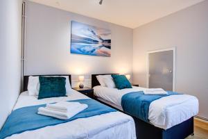 a bedroom with two beds with blue and white sheets at Statera Apartments - Studio Apartment in Walworth in London