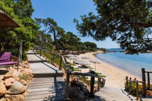 a wooden pathway to a beach with umbrellas and the water at Grand Hôtel De Cala Rossa & Spa Nucca in Porto-Vecchio