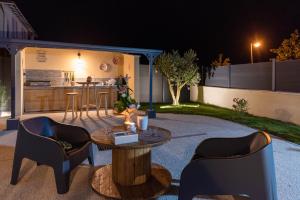 a backyard patio with a table and chairs at night at Villa des Oliviers Sublime villa avec piscine chauffée et privée et baby foot in Bon-Encontre