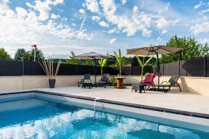 - une piscine avec des chaises et des parasols à côté dans l'établissement Villa des Oliviers : Sublime villa avec piscine chauffée et privée, terrasse de 185m², à Bon-Encontre