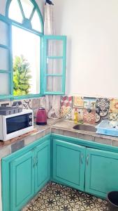 a kitchen with blue cabinets and a microwave at Art studio au bord de la mer in El Jadida