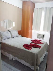 um quarto com uma cama com duas toalhas vermelhas em Apto acolhedor, confortável e bem localizado em Campos dos Goytacazes