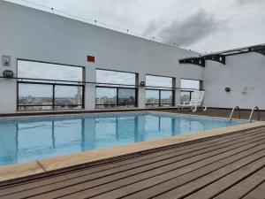 a large swimming pool in a building with windows at Apto acolhedor, confortável e bem localizado in Campos dos Goytacazes