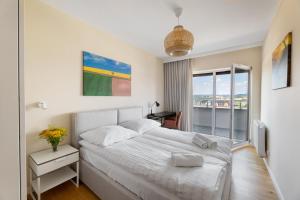 1 dormitorio con cama blanca y balcón en Apartament Widokowy - Penthouse z tarasem en Kudowa-Zdrój