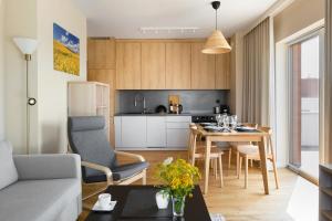 een keuken en een woonkamer met een tafel en stoelen bij Apartament Widokowy - Penthouse z tarasem in Kudowa-Zdrój