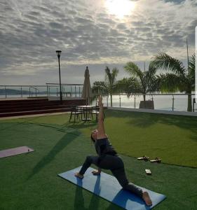 una mujer haciendo una pose de yoga en una esterilla de yoga cerca de la playa en Ecusuites Puerto Santa Ana Bed King Airport, en Guayaquil