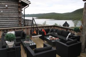 a deck with a couch and chairs and a fire pit at Kelo Aurora luxury cabin in Kilpisjärvi