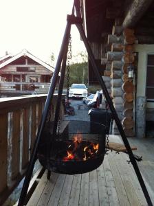 eine Feuerstelle auf einer Terrasse mit Grill in der Unterkunft Kelo Aurora luxury cabin in Kilpisjärvi