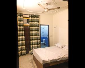 a bedroom with a bed and a ceiling fan at Malik Guest House By WB Inn in Gurgaon
