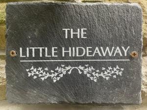 a stone sign that reads the little hidden pathway at The Little Hideaway - Historic Gem off Haworth Main Street in Haworth