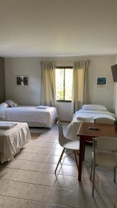 a bedroom with two beds and a desk and a table at Hosteria Andina in Esquel