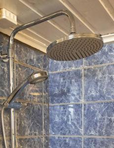 La salle de bains est pourvue d'une pomme de douche et de carrelage bleu. dans l'établissement Large, quiet and centrally located apartment, à Fredrikstad