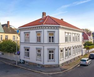 a white building with a red roof on a street at Large, quiet and centrally located apartment in Fredrikstad