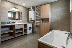 a bathroom with a tub and a sink and a washing machine at Apartament CALLUNA in Kudowa-Zdrój