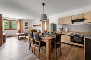 a kitchen with a wooden table and chairs in it at Apartament CALLUNA in Kudowa-Zdrój