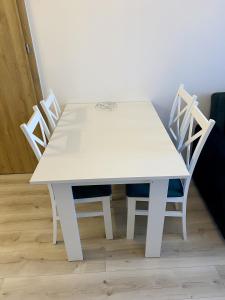 uma mesa de jantar branca com 4 cadeiras brancas em Szmaragdowy Zakątek em Glogów