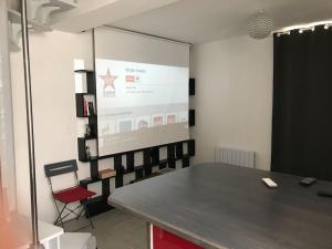 une salle de conférence avec une table et un écran de projection dans l'établissement Petite maison de Ville, à Auxerre