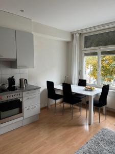uma cozinha com uma mesa e cadeiras brancas e uma janela em over-night City-Flat em St. Gallen