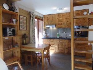 a kitchen with wooden cabinets and a wooden table at Charmant Appartement avec Mezzanine et Balcon - 4-5 Pers., Garage, Proche Lac et Navette - FR-1-198-121 in Châtel