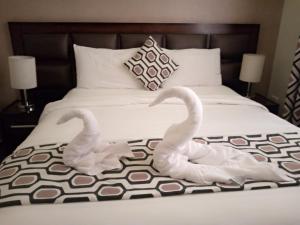 Dwa białe łabędzie siedzą na łóżku. w obiekcie Shams Alweibdeh Hotel Apartments w mieście Amman
