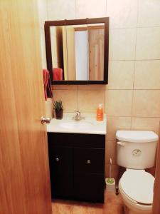 een badkamer met een toilet, een wastafel en een spiegel bij Hospedaje con vista a la ciudad in Monterrey