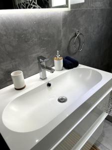 a white bathroom sink with two cups on it at Superbe appartement lumineux avec parking gratuit in Wintzenheim +8 photos