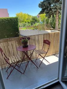 two chairs and a table with a potted plant on a patio at Superbe appartement lumineux avec parking gratuit in Wintzenheim