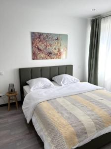 a bedroom with a bed and a painting on the wall at Superbe appartement lumineux avec parking gratuit in Wintzenheim