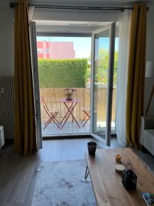 ein Wohnzimmer mit einem Tisch und einer Glasschiebetür in der Unterkunft Superbe appartement lumineux avec parking gratuit in Wintzenheim