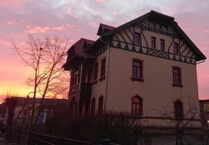een groot wit huis met een zonsondergang op de achtergrond bij Villa Weißbach - Haus Hilda in Flöha