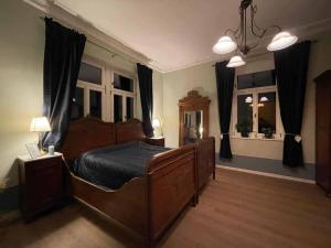 een slaapkamer met een groot houten bed en 2 ramen bij Villa Weißbach - Haus Hilda in Flöha