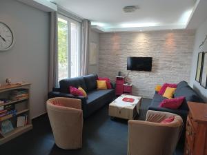 ein Wohnzimmer mit einem Sofa, Stühlen und einem TV in der Unterkunft La maison d'adèle in Sancerre