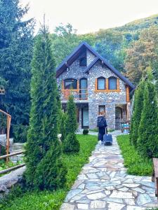 a woman walking in front of a stone house at Chalet Kujta in Peje