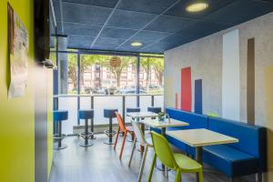 ein Restaurant mit Tischen und Stühlen und einem Fenster in der Unterkunft B&B HOTEL Troyes Centre in Troyes