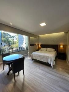 a bedroom with a bed and a desk and a table at Residencial Jardim dos Pinheiros B in Canela