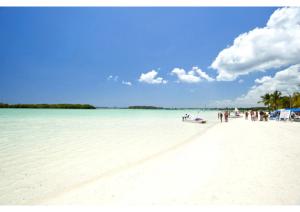 a group of people standing on a white beach at Terrazas del Caribe, Boca Chica. in Boca Chica